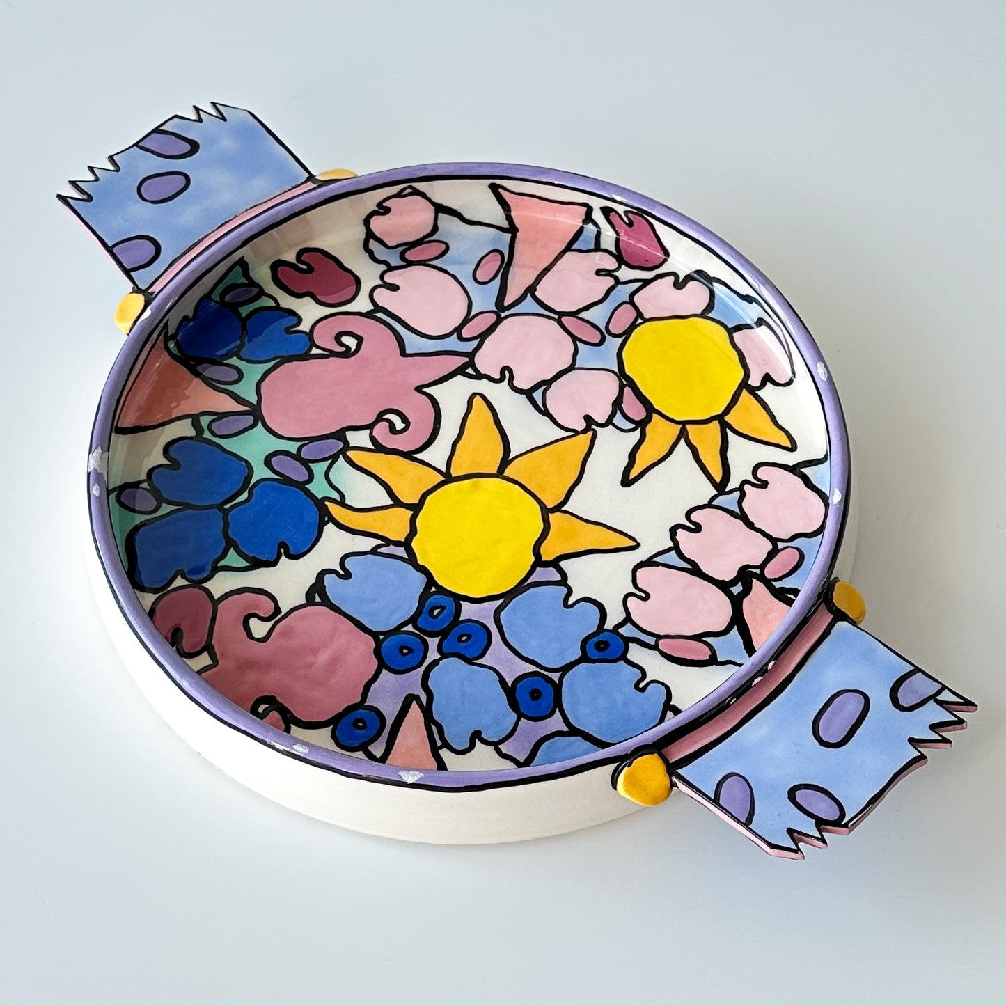 A ceramic catchall vide poche with a colorful floral and geometric pattern, featuring a signature on the underside.